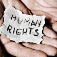 closeup of the hands of a young man with a piece of paper with the text human rights written in it, with a dramatic effect